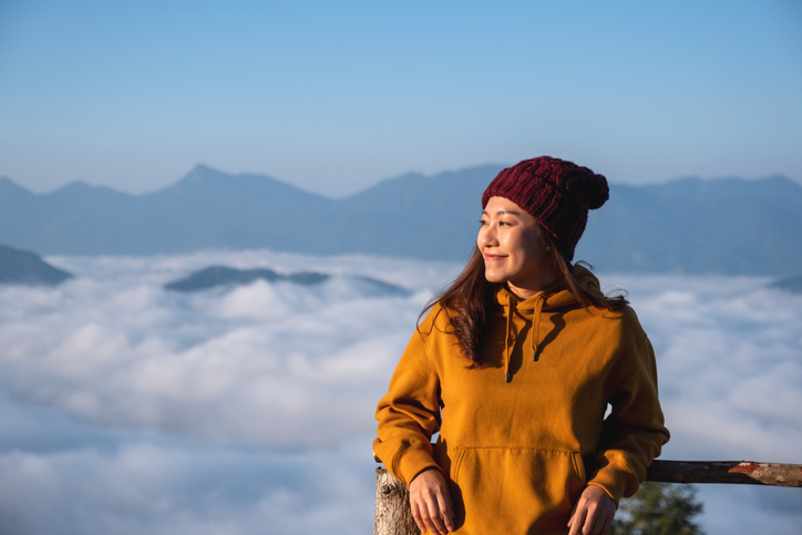 Portrait of a young female traveler with a beautiful mountain and sea of fog in the morning Hospitality Trends Post COVID
