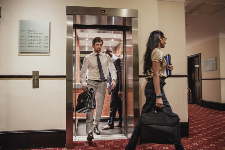 Businessmen and businesswomen walking out the lift at the hotel after a business meeting.